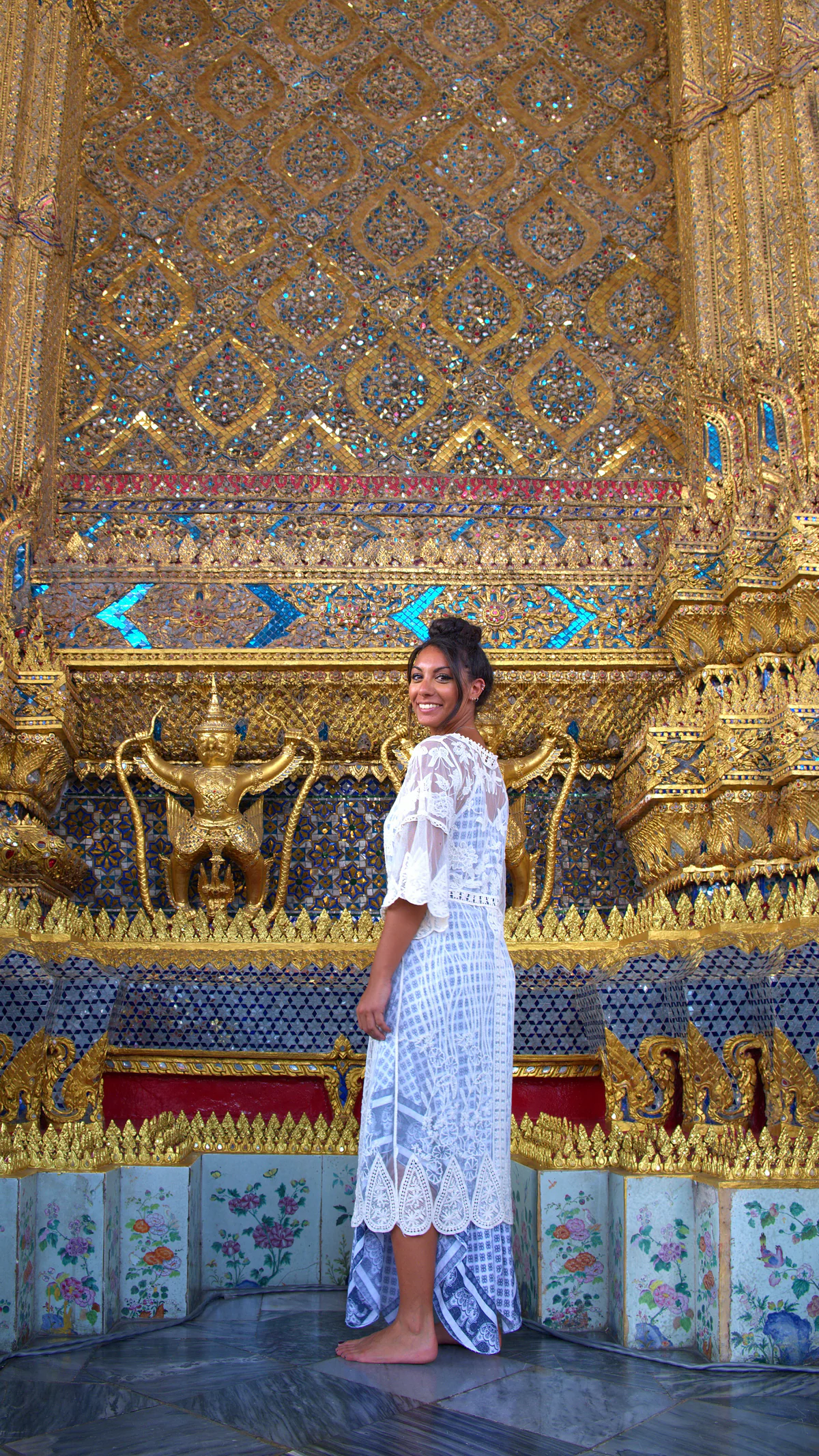 Samira in a white dress in front of the golden wall of a temple