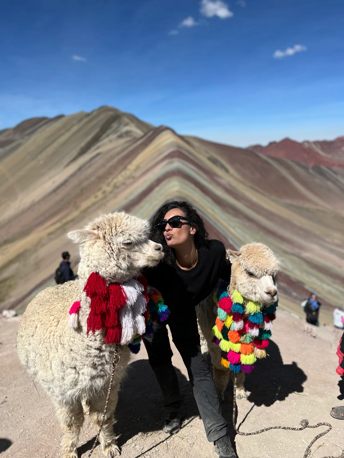 Samira con due alpaca decorati sulla Montagna Arcobaleno, in Perù