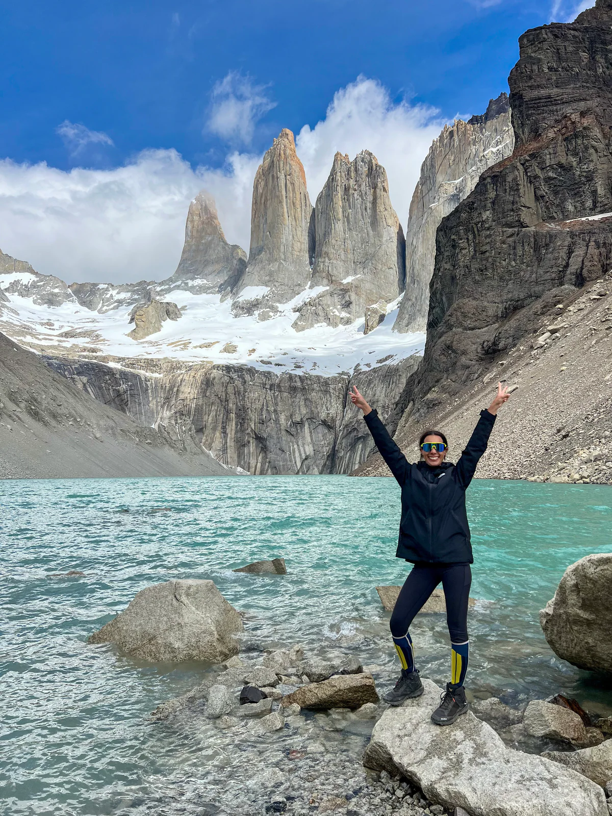 Samira a braccia aperte sulle rocce del lago, davanti alle Torri del Paine