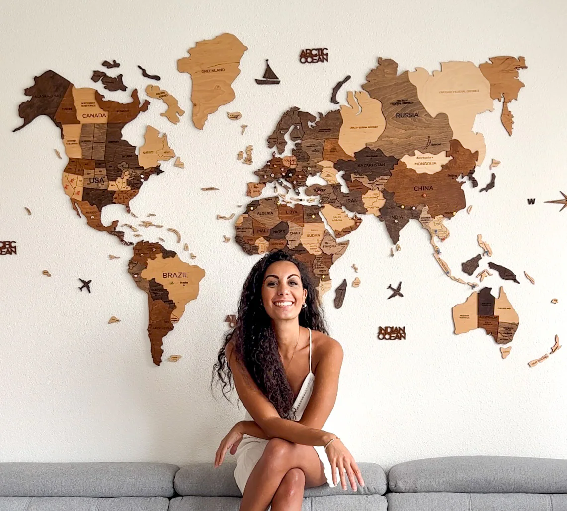 Samira smiling, sitting in front of a wooden world map